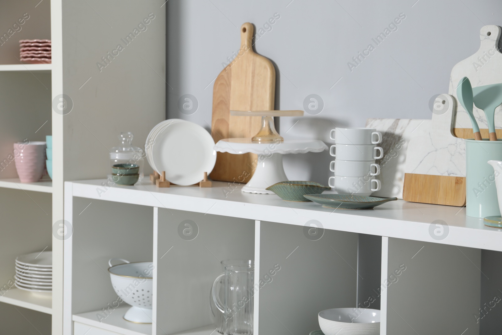 Photo of Shelving unit with kitchenware near grey wall indoors