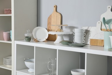 Shelving unit with kitchenware near grey wall indoors