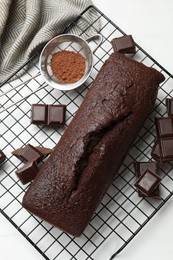 Photo of Tasty chocolate sponge cake and ingredients on white marble table, flat lay