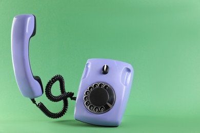 Photo of One violet telephone with handset on green background, space for text