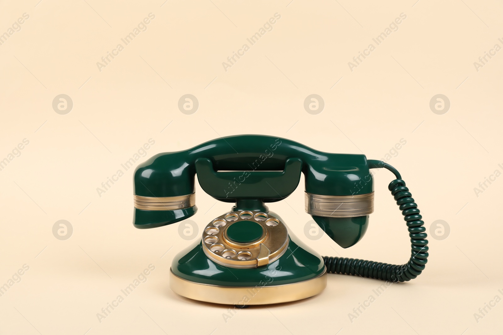 Photo of One green telephone with handset on beige background