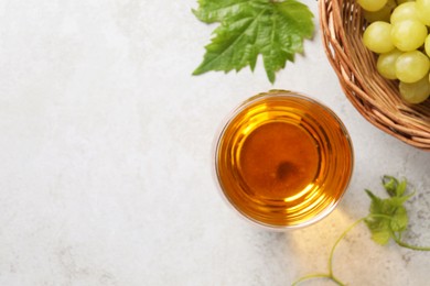 Tasty grape juice in glass, leaves and berries on light table, flat lay. Space for text