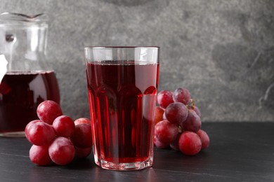 Photo of Tasty grape juice and berries on dark textured table, closeup