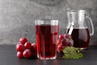 Tasty grape juice, leaf and berries on dark textured table