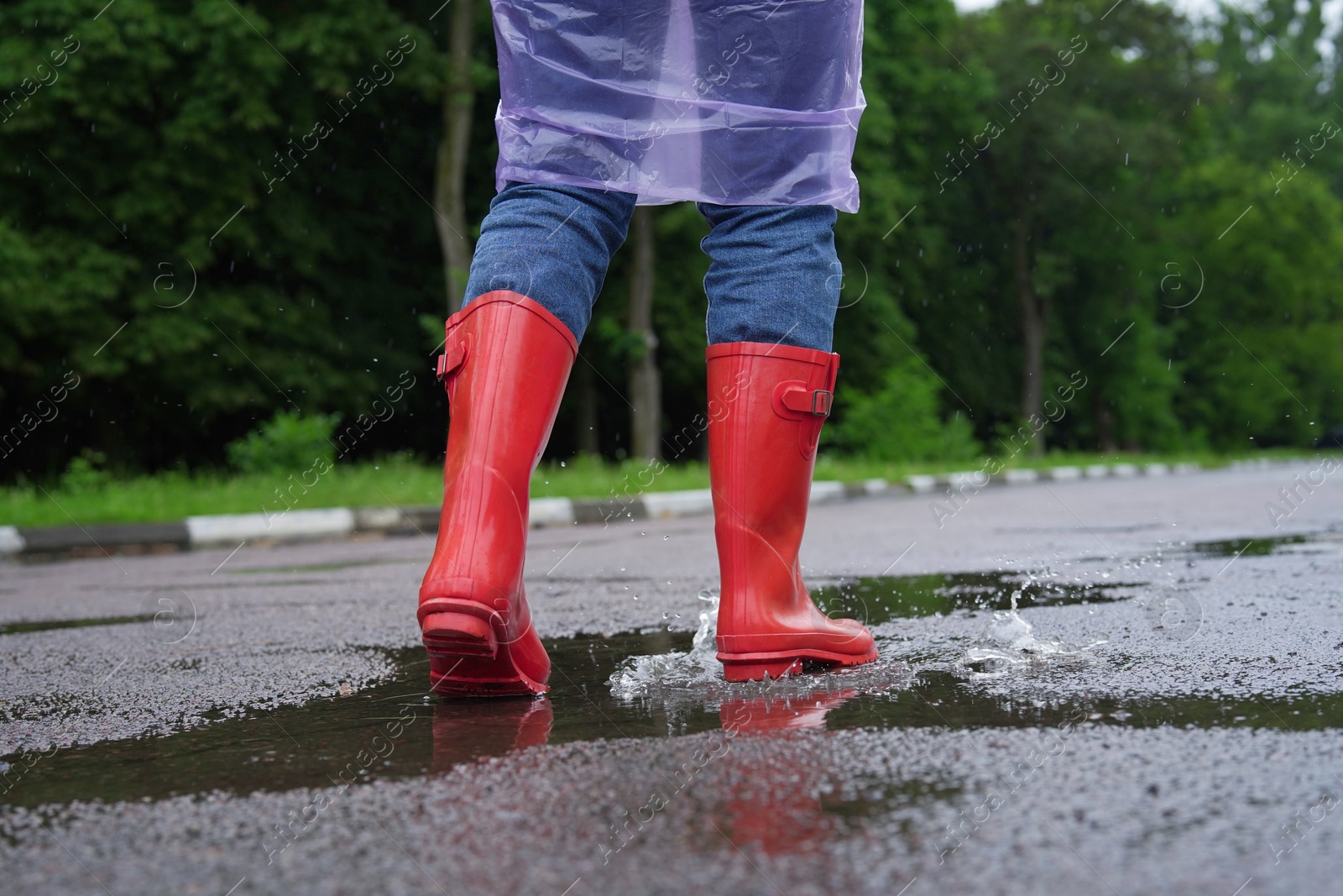 Photo of Woman in red rubber boots walking outdoors, closeup