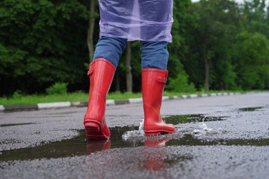 Woman in red rubber boots walking outdoors, closeup