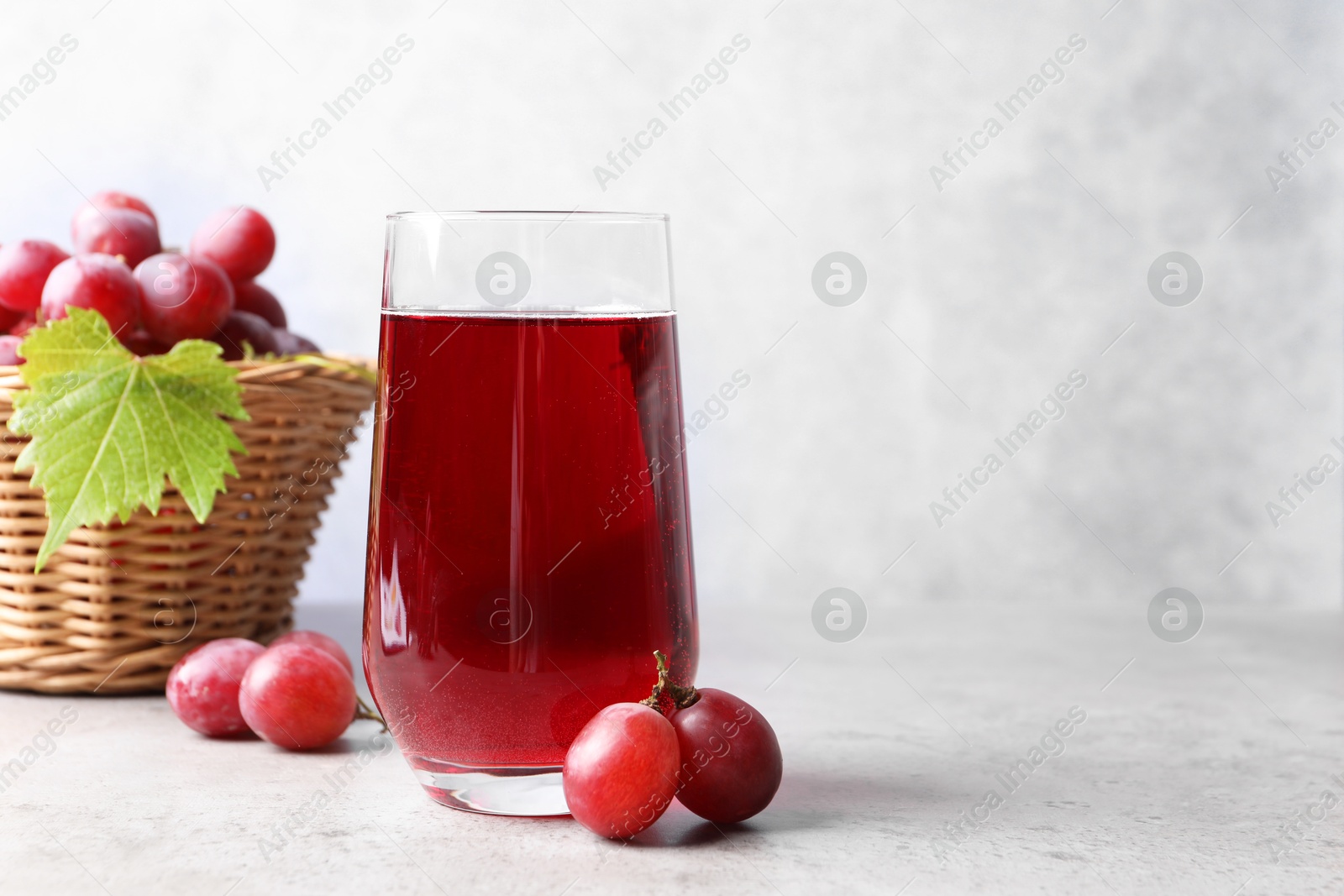 Photo of Ripe grapes and tasty juice on grey table. Space for text