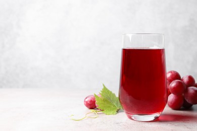 Photo of Ripe grapes and tasty juice on grey table. Space for text