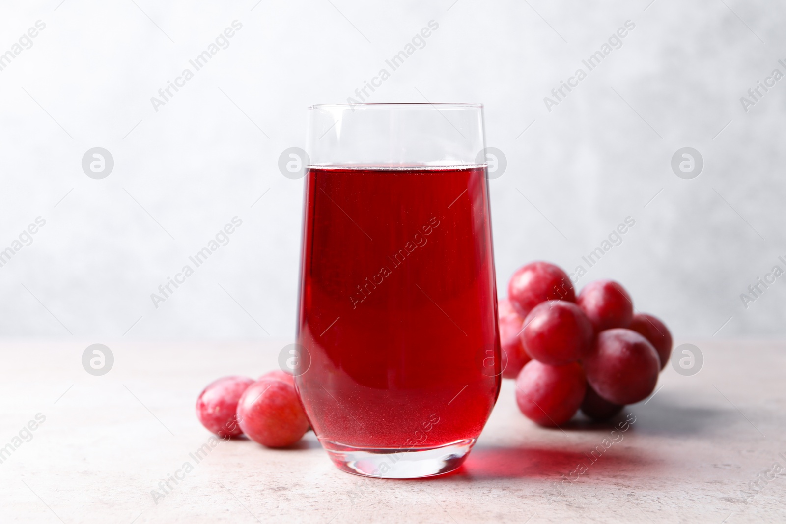 Photo of Ripe grapes and tasty juice on grey table