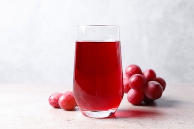 Photo of Ripe grapes and tasty juice on grey table