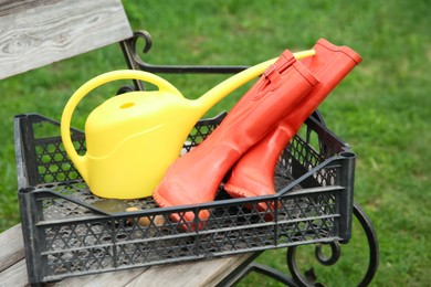 Photo of Orange rubber boots and gardening tools in crate outdoors