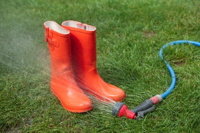 Orange rubber boots under water pressure on green grass outdoors