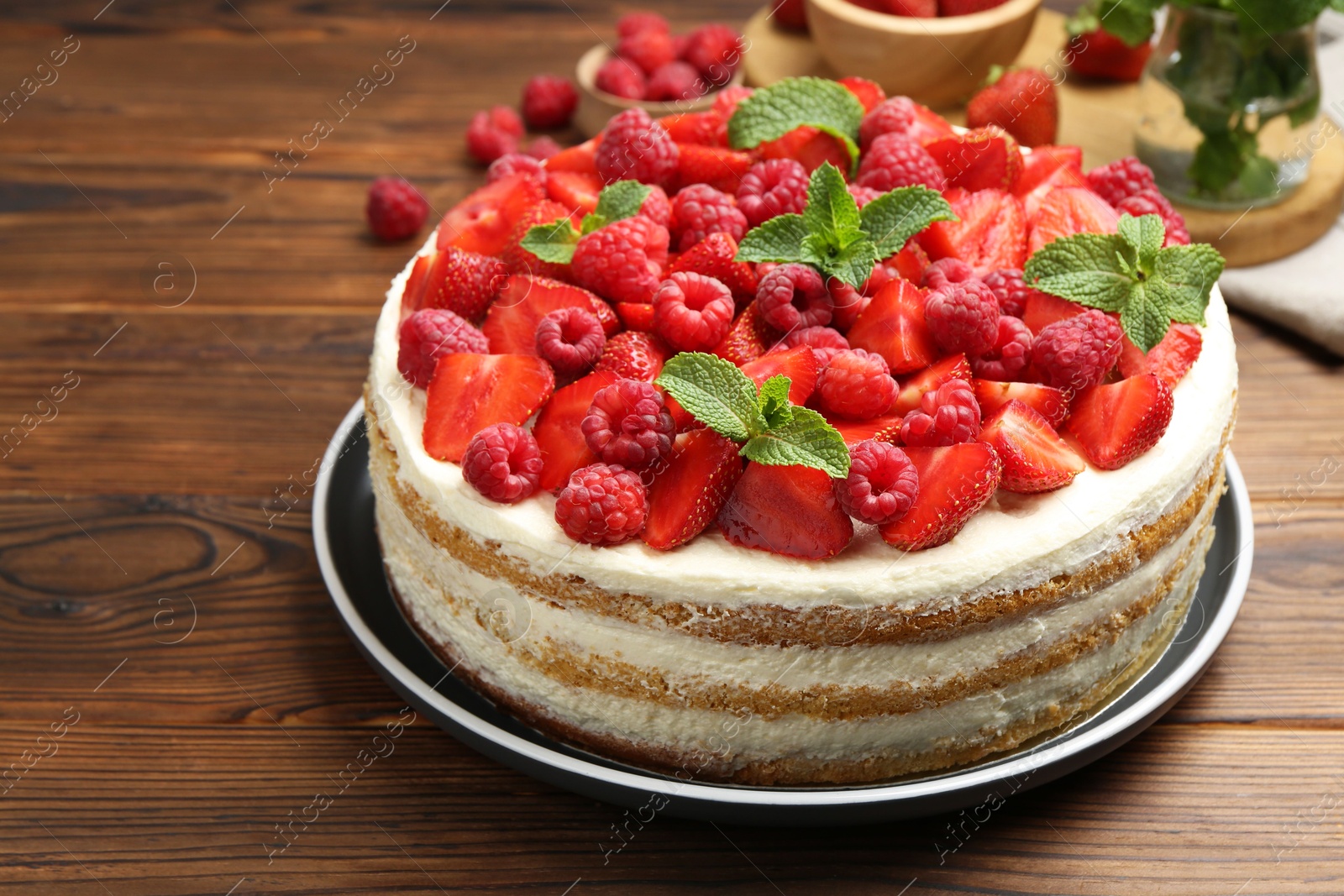 Photo of Tasty sponge cake with fresh berries and mint on wooden table, closeup