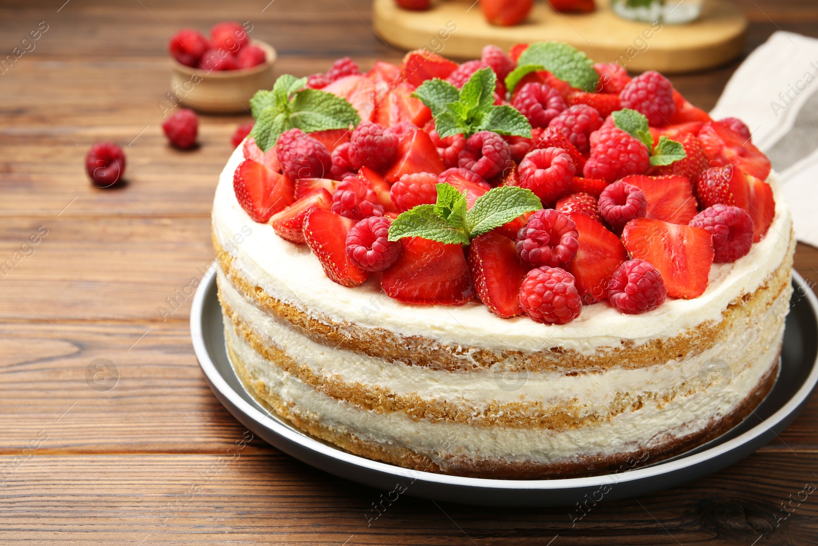 Photo of Tasty sponge cake with fresh berries and mint on wooden table, closeup