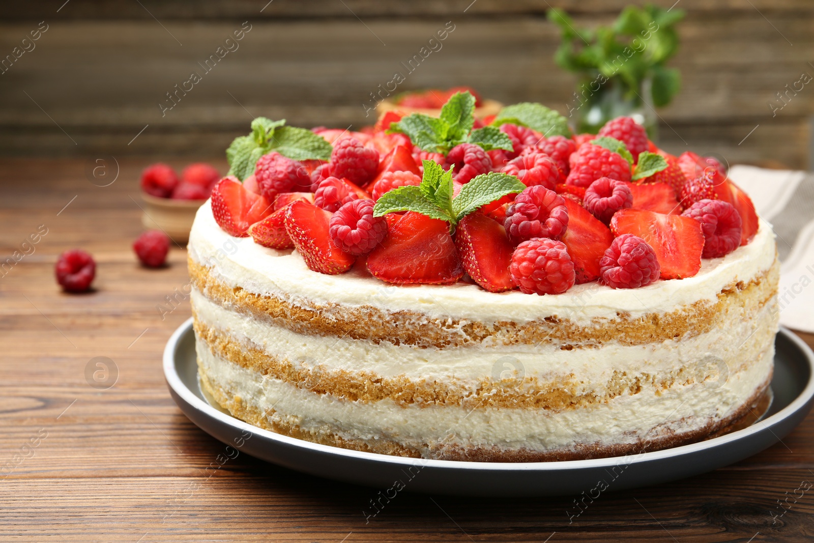 Photo of Tasty sponge cake with fresh berries and mint on wooden table, closeup