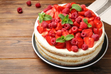 Tasty sponge cake with fresh berries and mint on wooden table, closeup