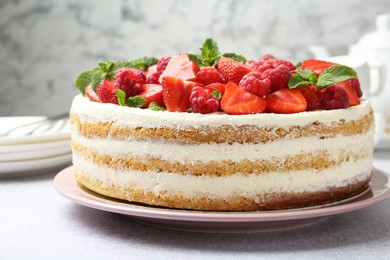 Photo of Tasty sponge cake with fresh berries and mint on light gray table