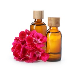 Photo of Geranium essential oil in bottles and beautiful flowers isolated on white