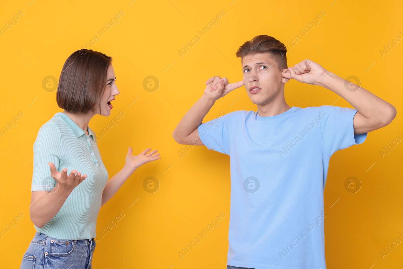 Photo of Emotional young couple arguing on orange background