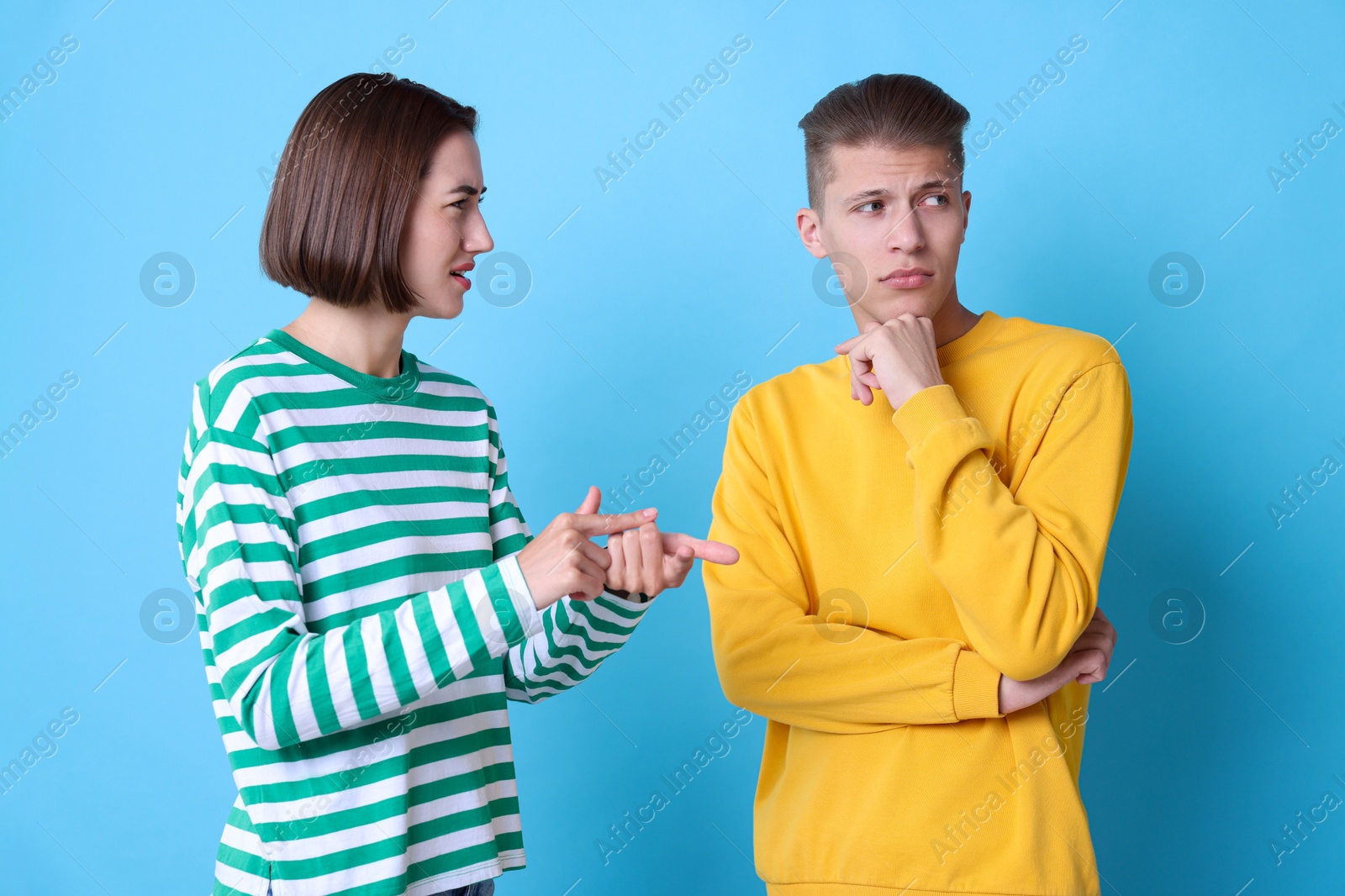 Photo of Emotional young couple having quarrel on light blue background