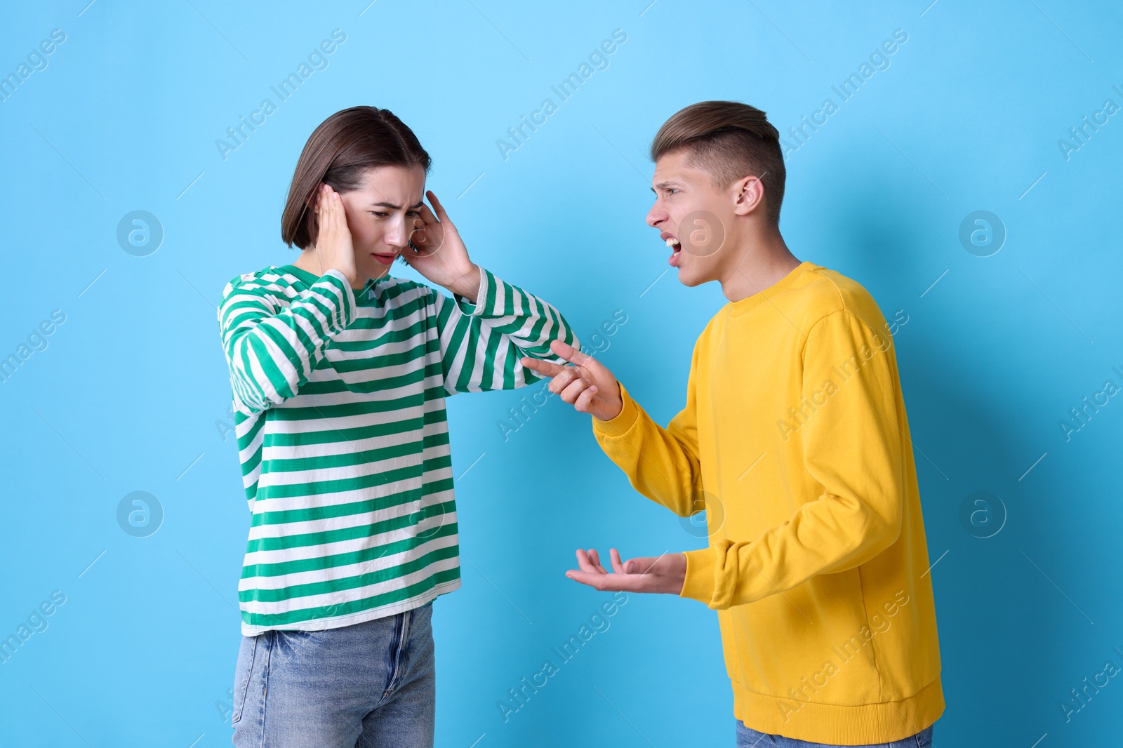 Photo of Emotional young couple having quarrel on light blue background