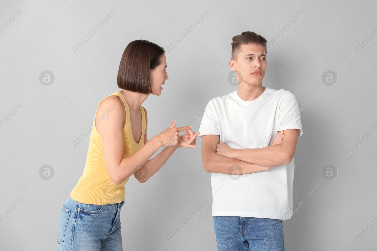 Photo of Emotional young couple having quarrel on grey background