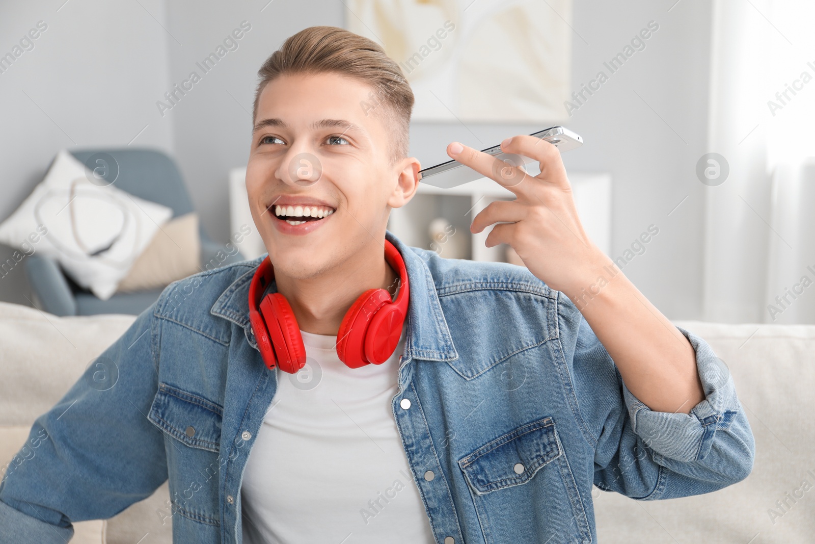 Photo of Young man with smartphone listening to voice message at home