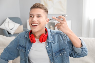 Photo of Young man with smartphone listening to voice message at home