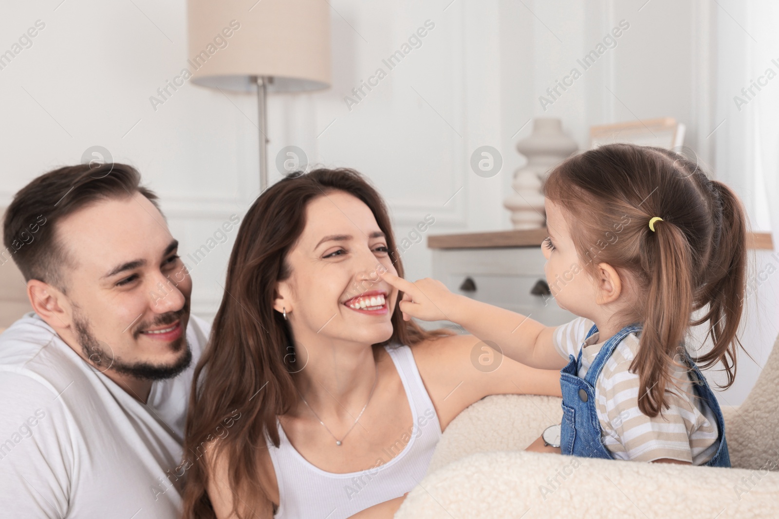 Photo of Happy family. Parents and their cute little daughter at home