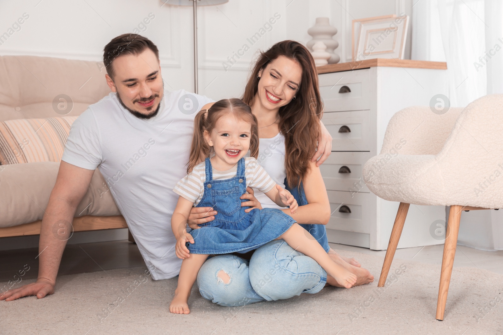 Photo of Happy family. Parents and their cute little daughter at home