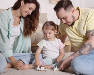 Happy family. Parents and their cute little daughter playing with toy train at home