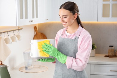 Photo of Beautiful young woman wiping toaster with rag in kitchen