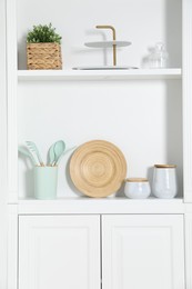 Photo of White shelving unit with different kitchenware indoors