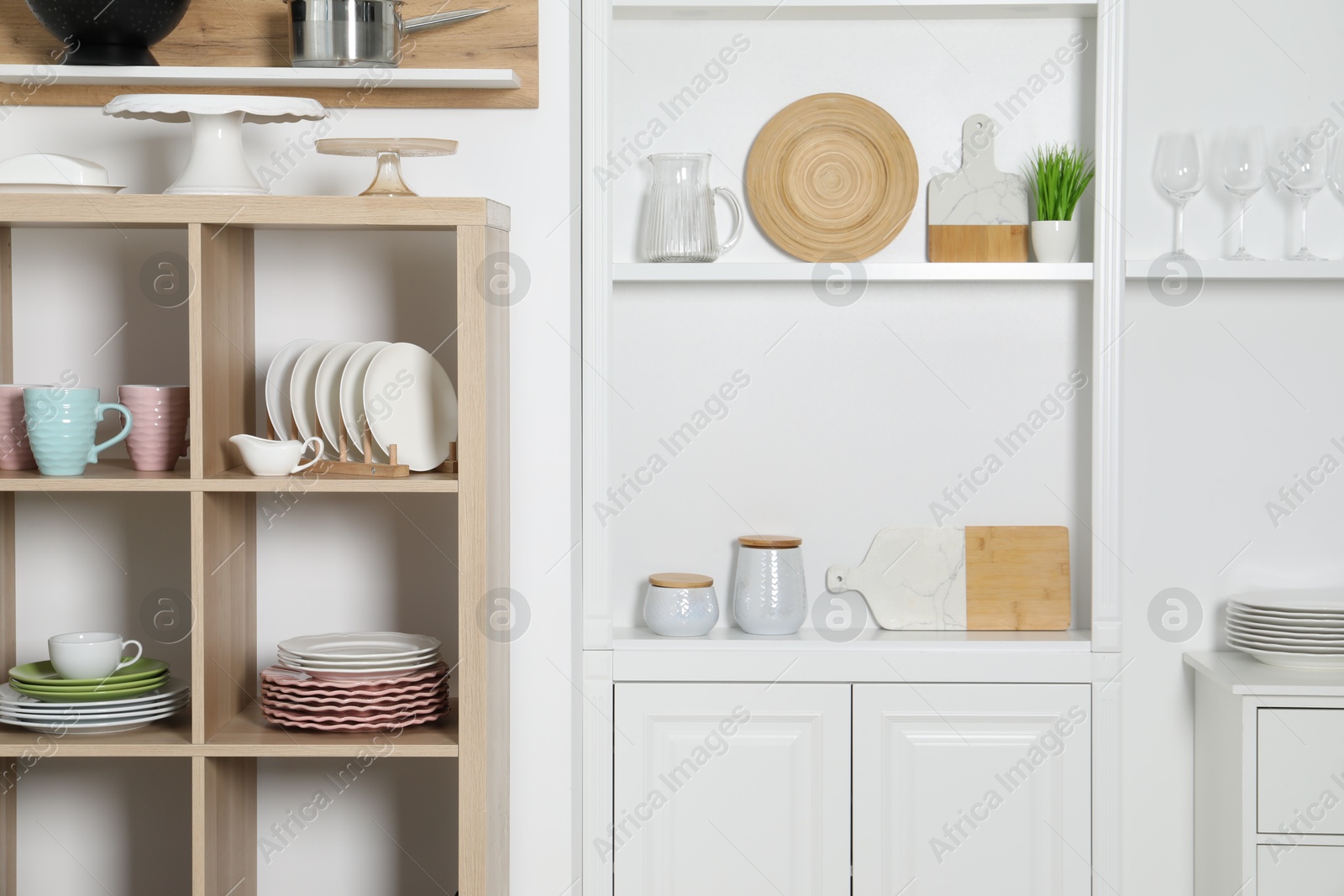 Photo of Shelving units with kitchenware near white wall indoors