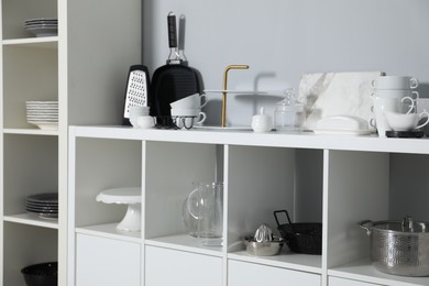 Shelving unit with kitchenware near grey wall indoors