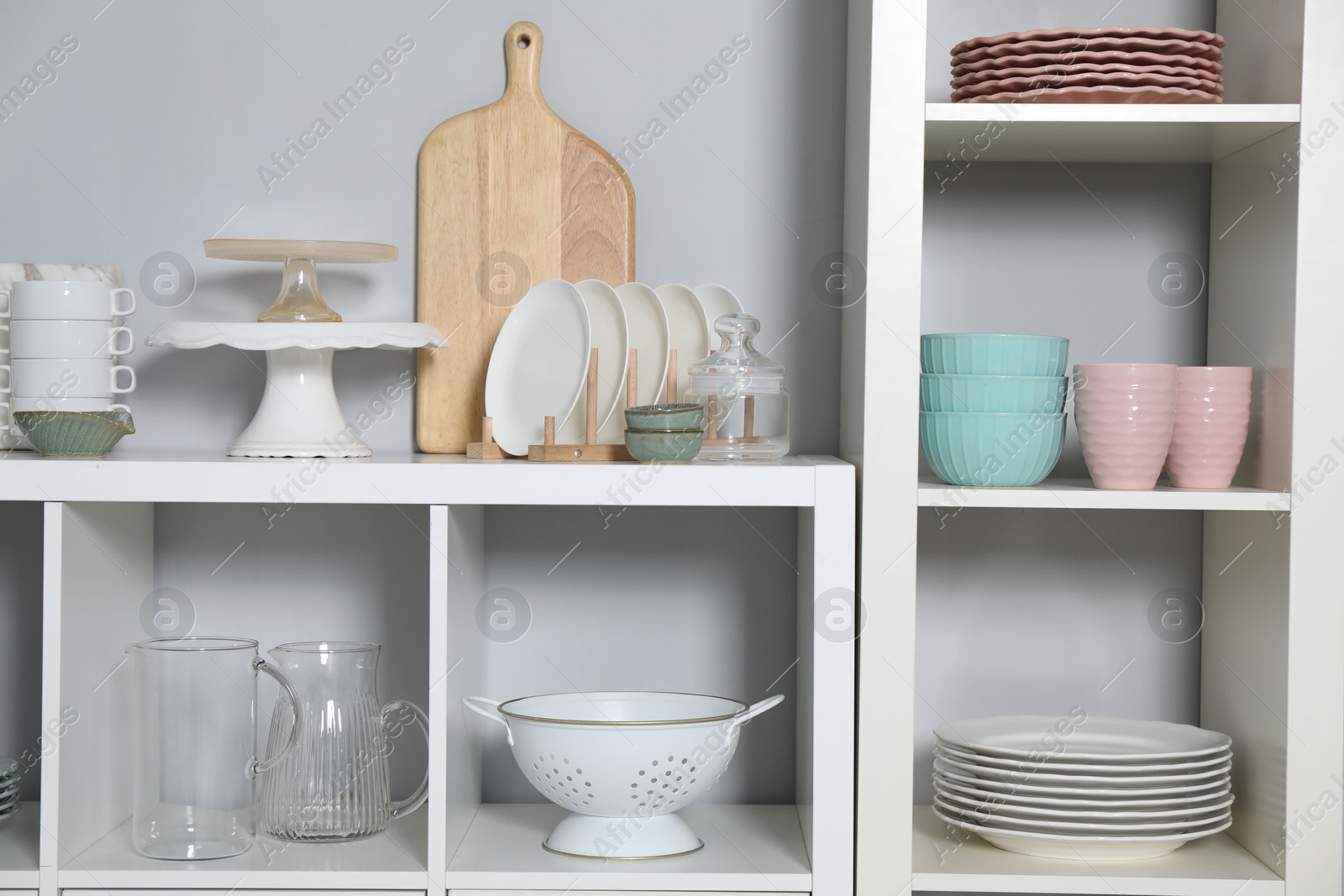 Photo of Shelving unit with kitchenware near grey wall indoors