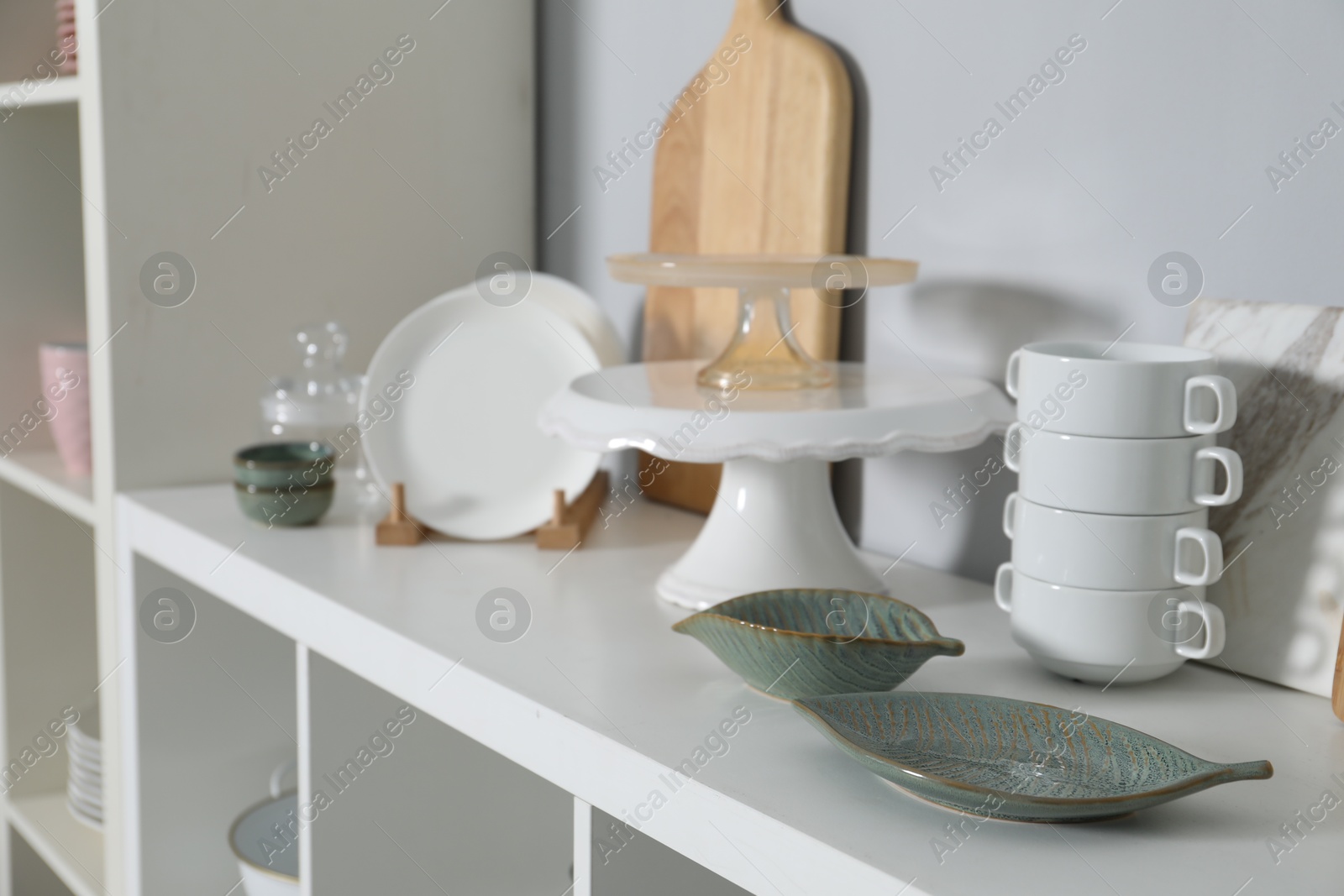 Photo of Shelving unit with kitchenware near grey wall indoors