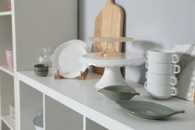 Shelving unit with kitchenware near grey wall indoors