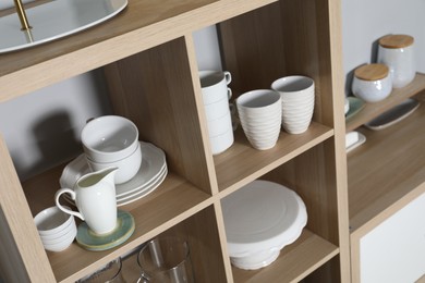 Wooden shelving unit with kitchenware near grey wall indoors