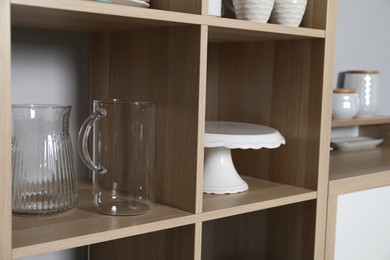 Wooden shelving unit with kitchenware near grey wall indoors