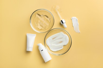 Photo of Petri dishes with cosmetic products and pipette on yellow background, flat lay