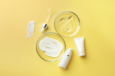 Photo of Petri dishes with cosmetic products and pipette on yellow background, flat lay