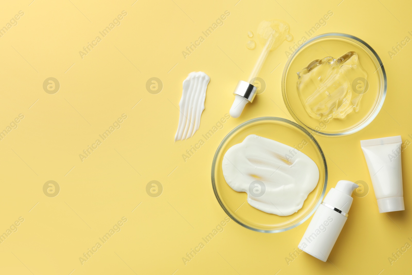 Photo of Petri dishes with cosmetic products and pipette on yellow background, flat lay. Space for text