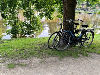 Photo of Bicycles parked at tree near canal outdoors