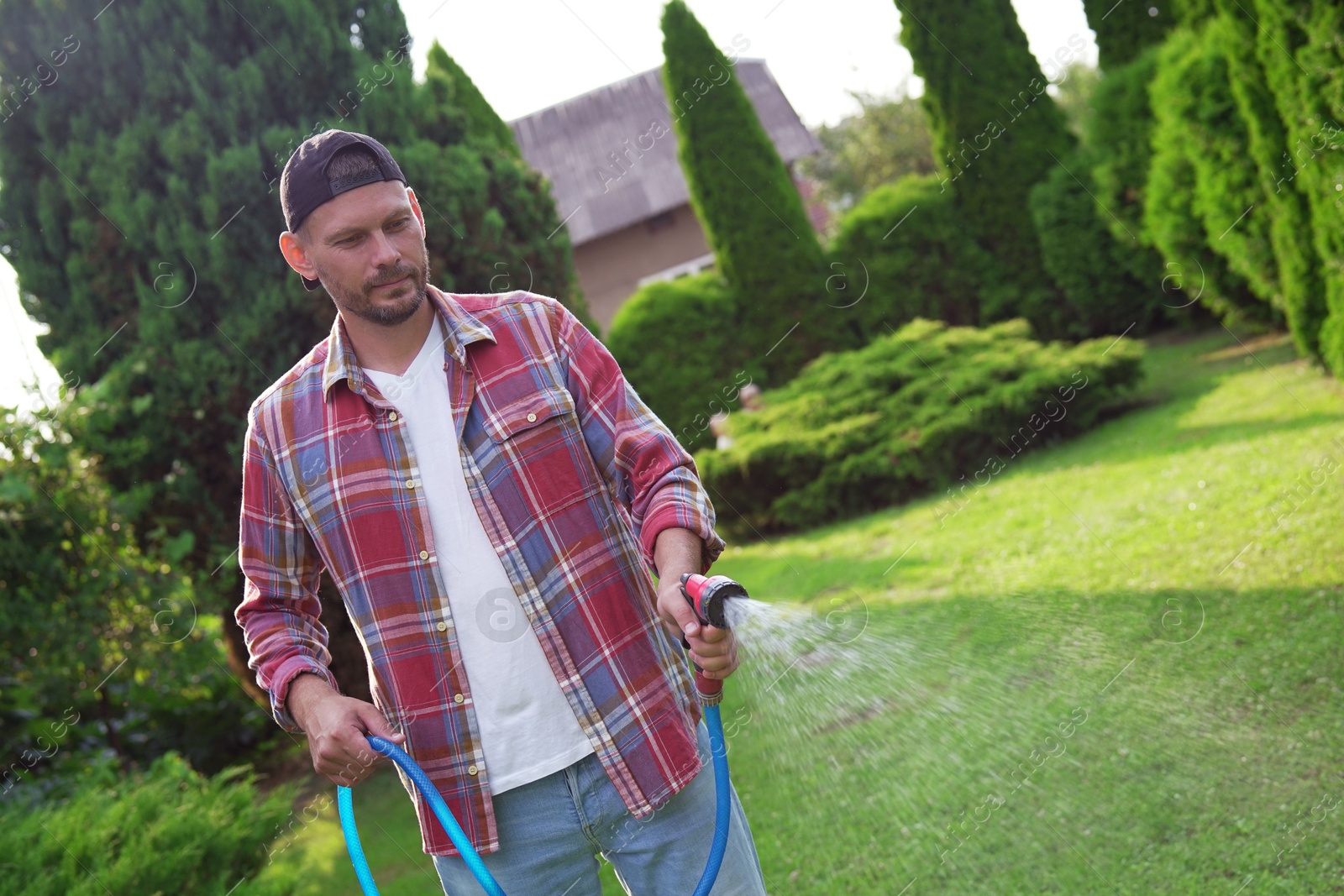 Photo of Man watering lawn with hose in backyard, space for text