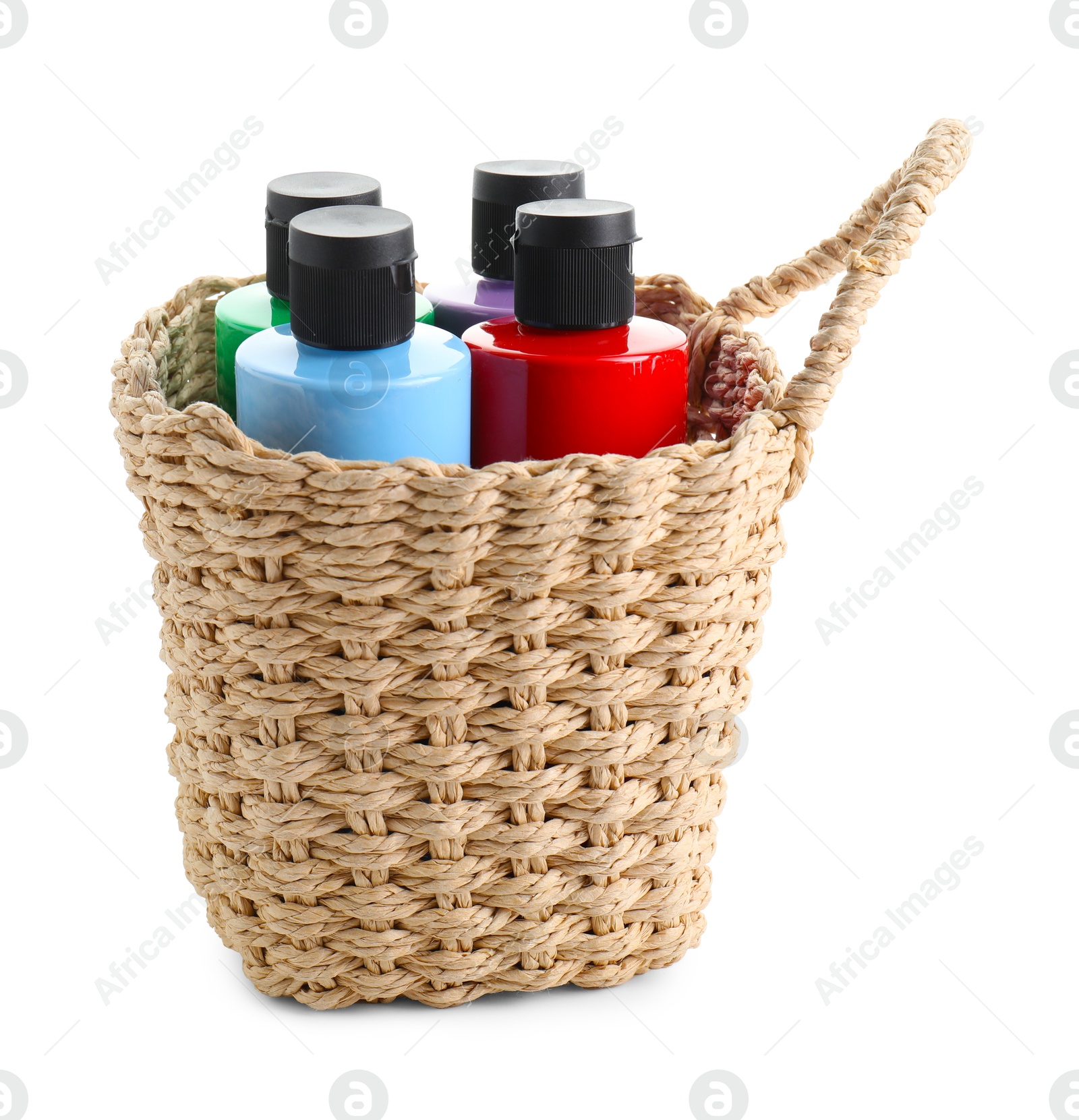 Photo of Bottled acrylic paints of different colors in wicker basket isolated on white