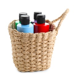 Bottled acrylic paints of different colors in wicker basket isolated on white