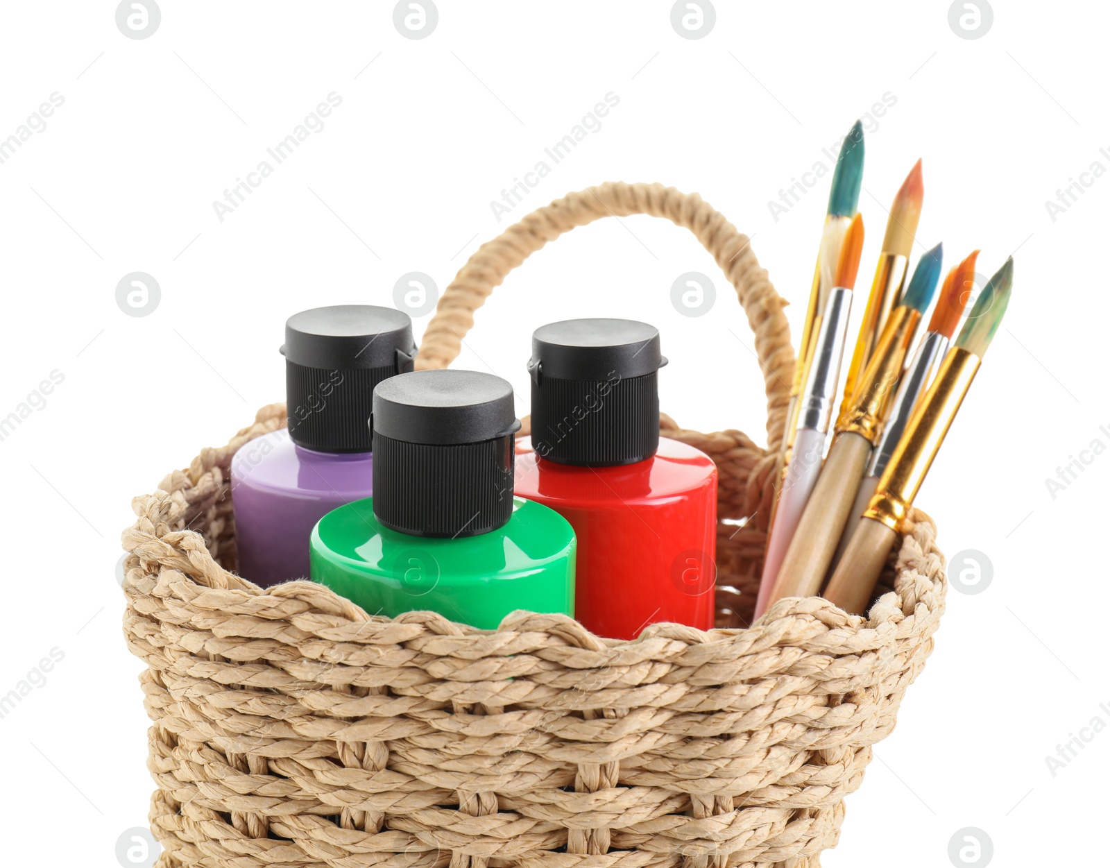 Photo of Acrylic paints of different colors and brushes in wicker basket isolated on white