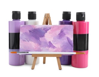 Photo of Acrylic paints of different colors in bottles and small easel with abstract picture isolated on white