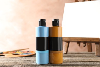 Photo of Acrylic paints of different colors in bottles on wooden table